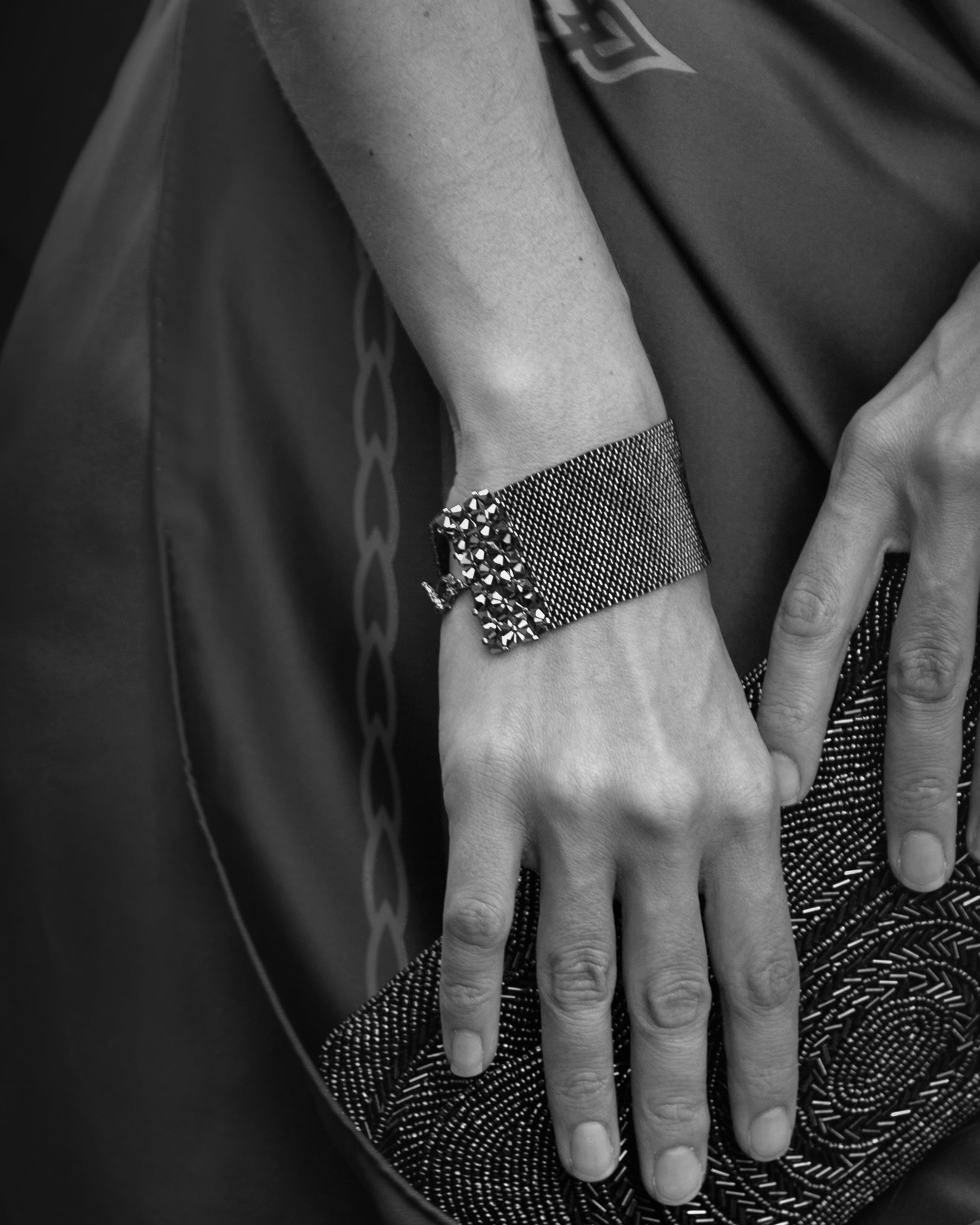 Close-up of a hand wearing a textured bracelet with a dark background
