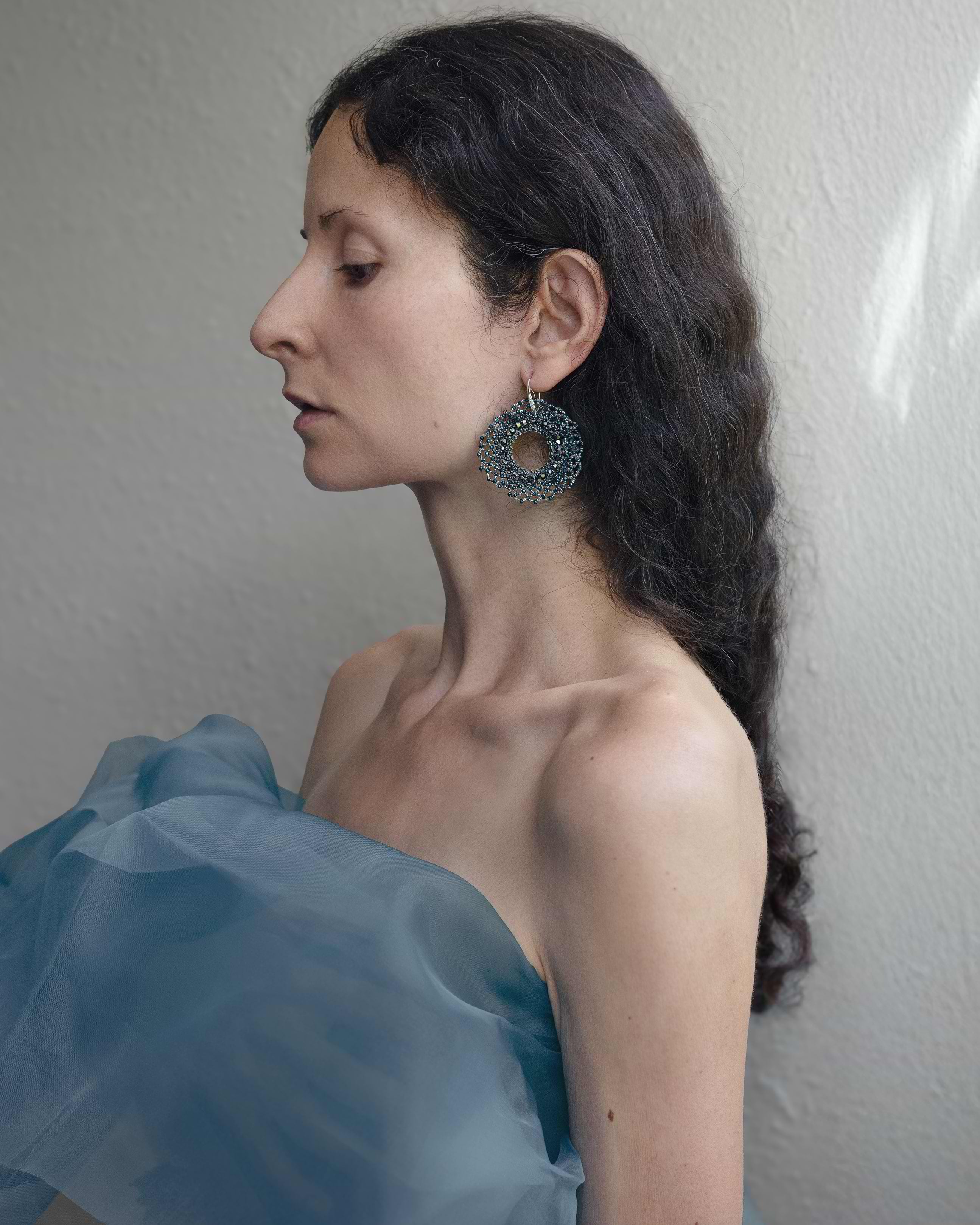 Woman wearing large hoop earrings with a plain background