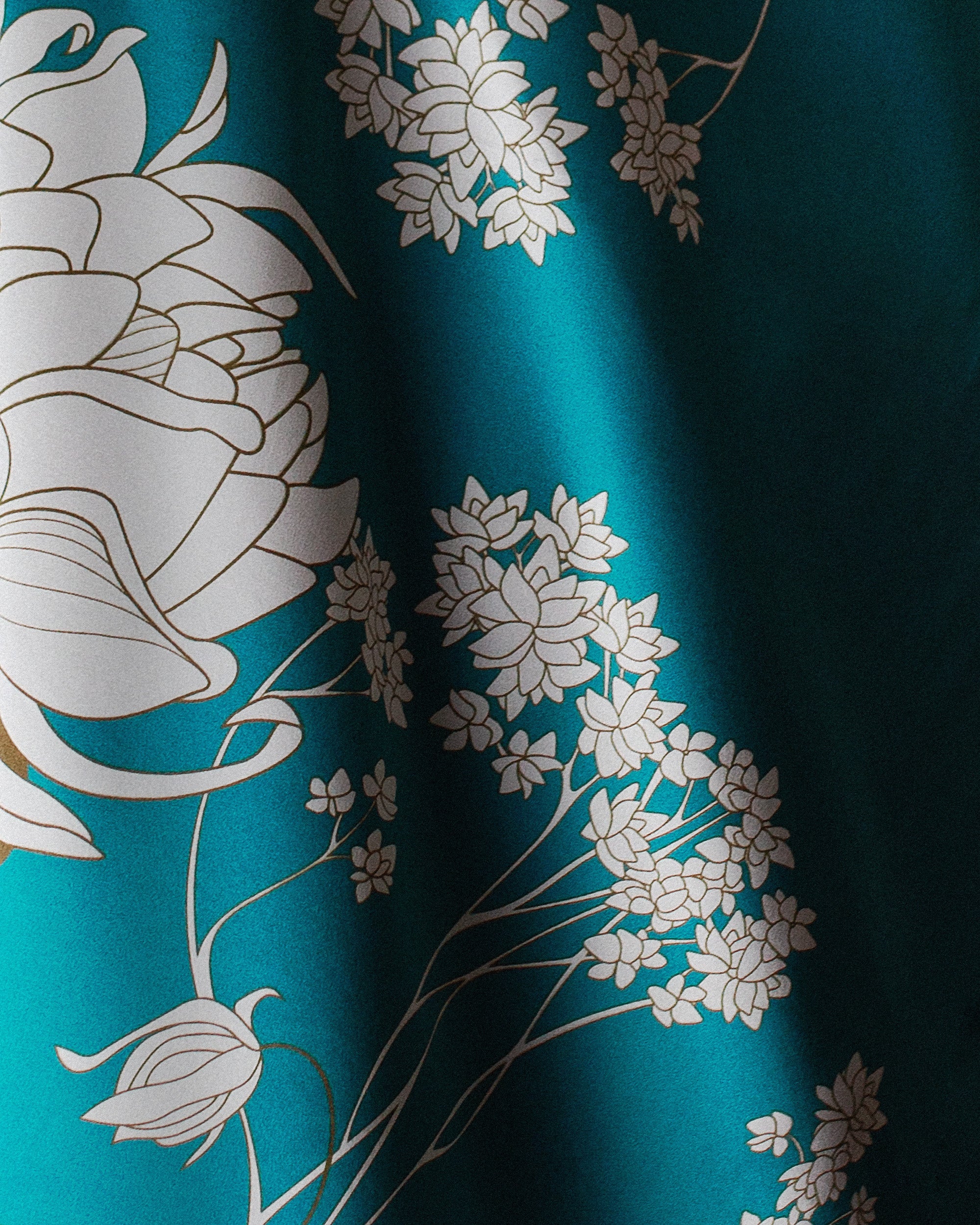 Close-up of a silk fabric with floral patterns on a teal background