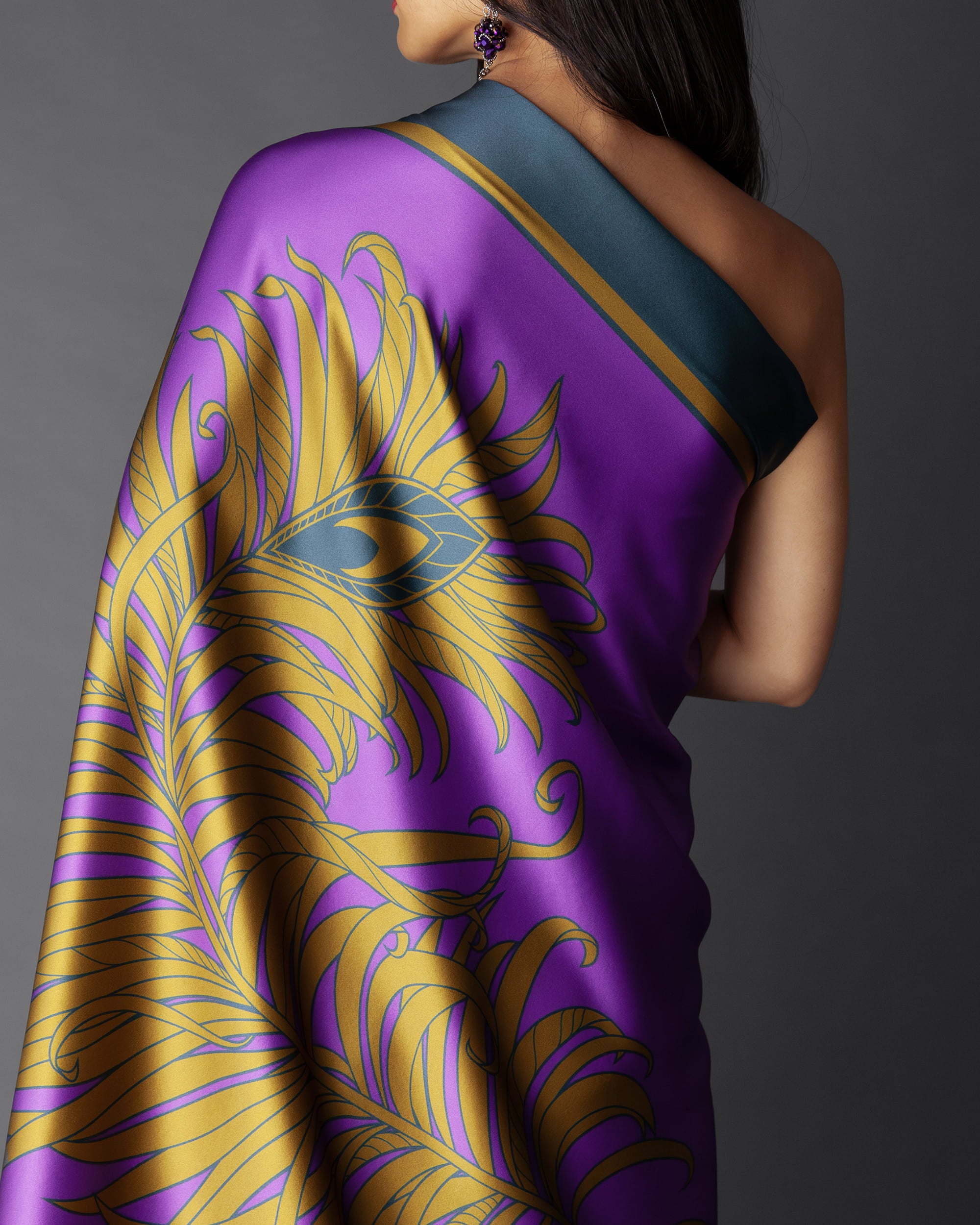 A person wearing an imperial purple feather silk foulard with gold patterns on it, draped over the shoulders.