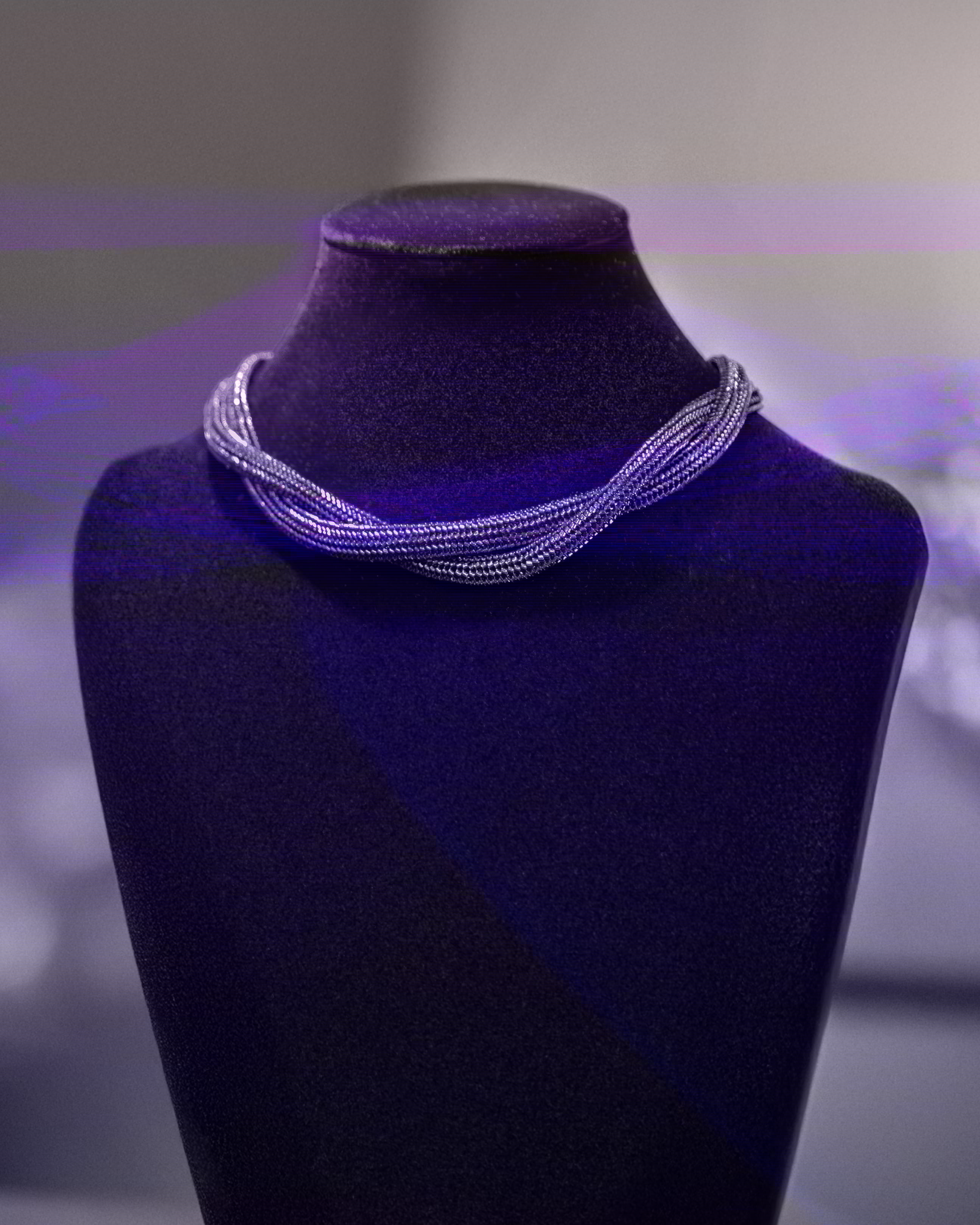 Necklace on a purple mannequin bust with a blurred background