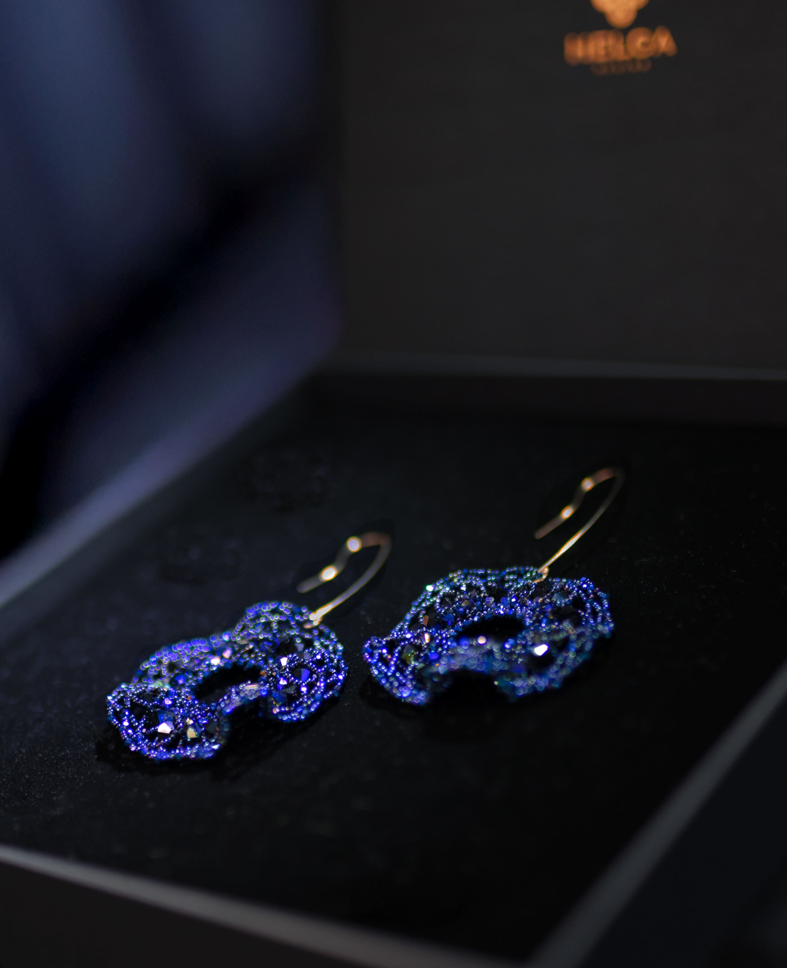 Blue gemstone earrings on a dark surface with a blurred background
