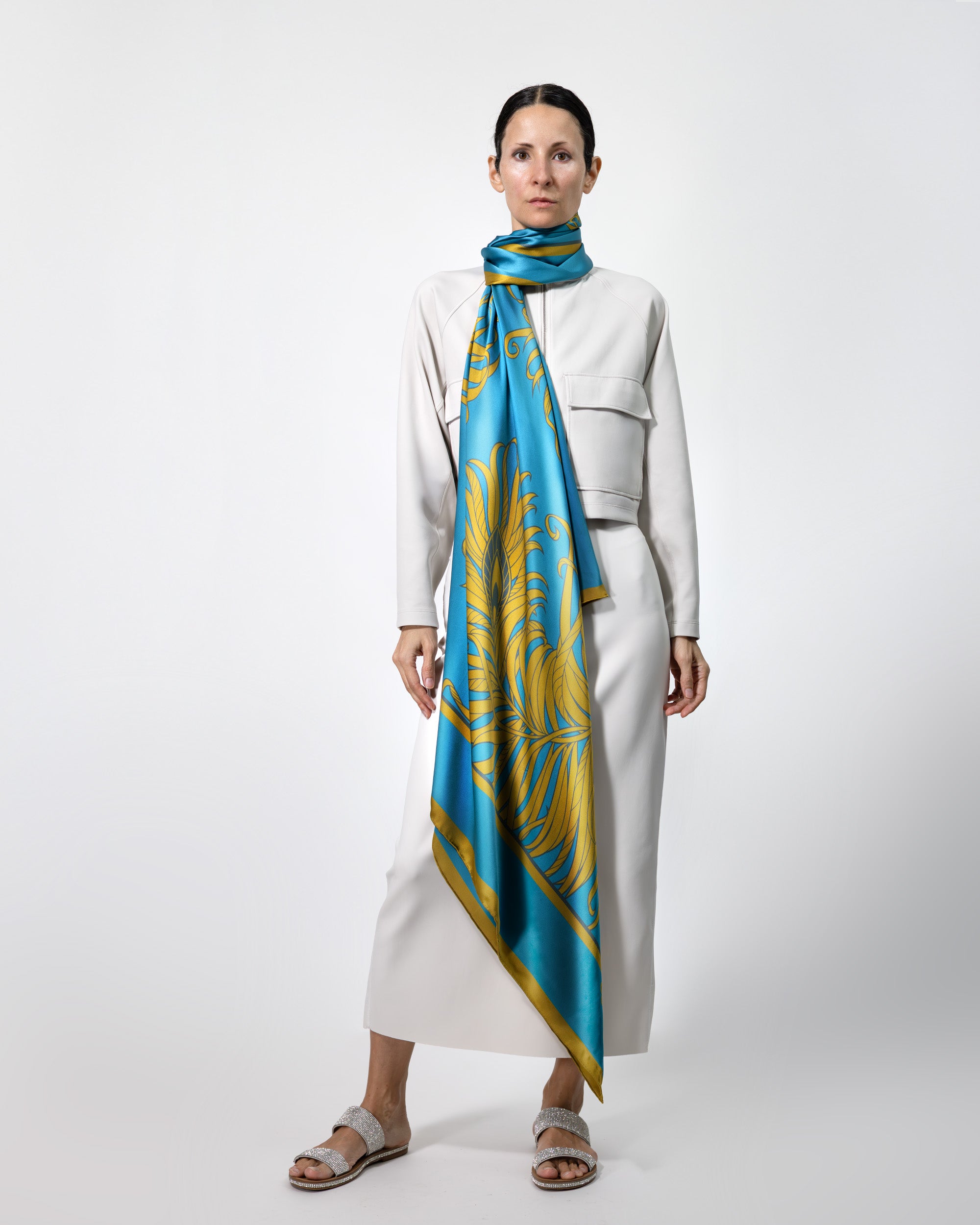 Woman wearing a white outfit with a blue and gold patterned scarf on a white background